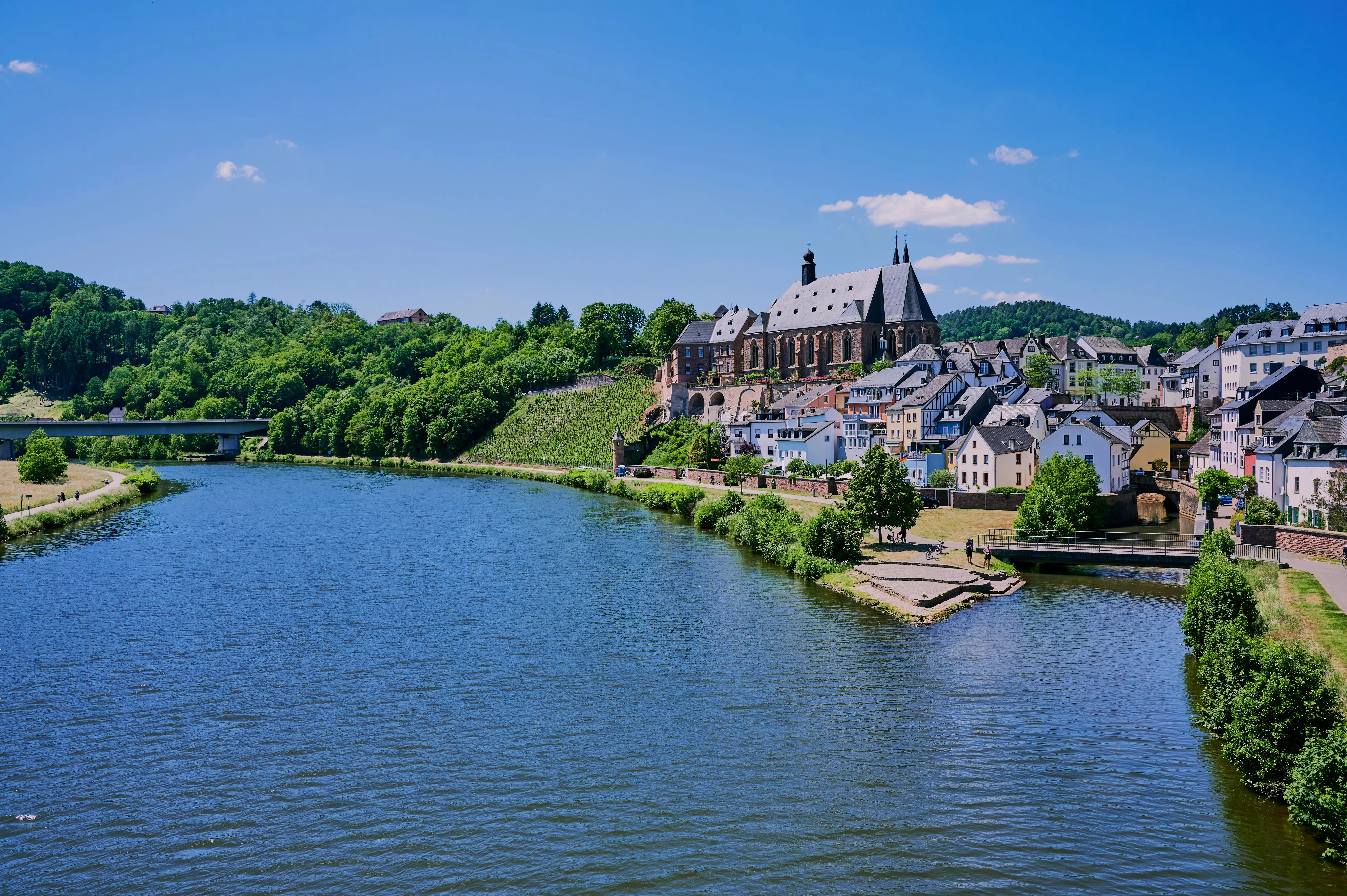 Uitzicht op het charmante Saarburg met vakwerkhuizen en kerk, gelegen aan de rivier op een zonnige dag.