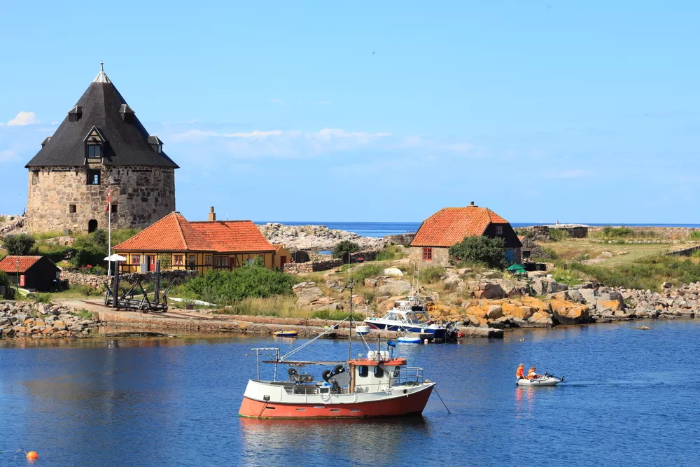 houten vissersbot in het water en oude stenen toren op de achtergrond